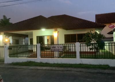 Exterior view of a single-story house at dusk with a front lawn and a gate