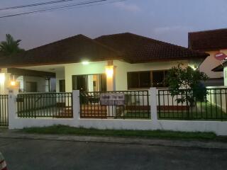 Exterior view of a single-story house at dusk with a front lawn and a gate