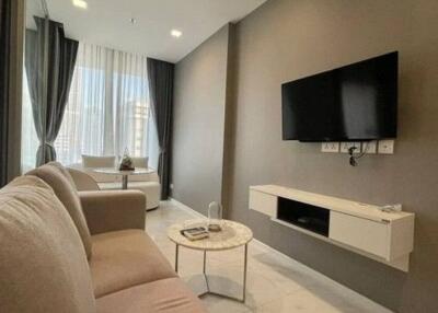 Modern living room with wall-mounted TV, coffee table, and a large window