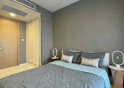 Contemporary styled bedroom with gray walls and bedding, featuring minimalist bedside tables and modern lighting fixtures.