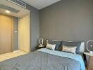 Contemporary styled bedroom with gray walls and bedding, featuring minimalist bedside tables and modern lighting fixtures.