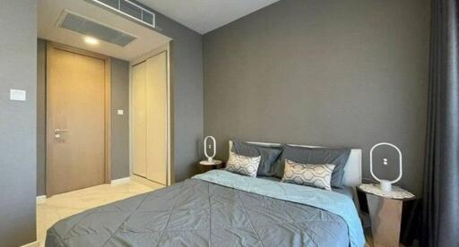 Contemporary styled bedroom with gray walls and bedding, featuring minimalist bedside tables and modern lighting fixtures.