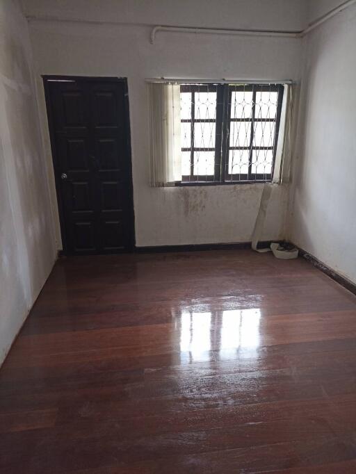 Empty bedroom with wooden floor and barred windows