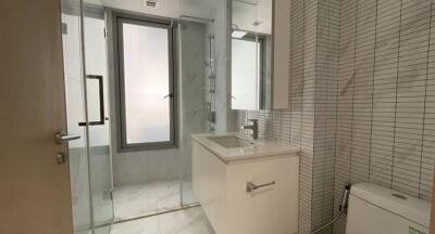 Modern bathroom with glass shower, white vanity, and tiled walls