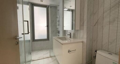 Modern bathroom with glass shower, white vanity, and tiled walls