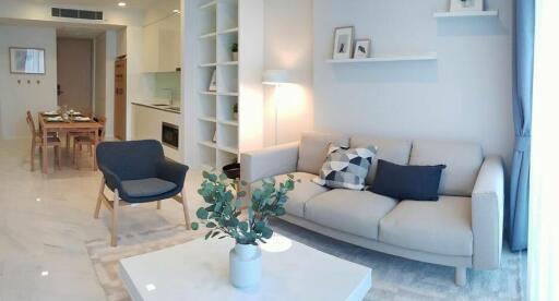 Modern living room with a beige sofa, armchair, coffee table, and an adjacent open dining area