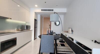 Modern kitchen and dining area with gray chair, dining table, and built-in appliances