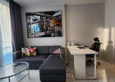 Modern living room with sofa, glass coffee table, desk, and wall art