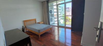 Bedroom with bed, desk and large windows leading to a balcony