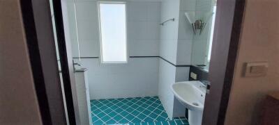 A small bathroom with a sink, window, and wall-mounted light fixture