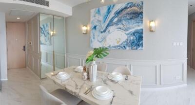 Elegant dining area with marble table and abstract ocean-themed art