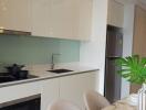 Modern kitchen with white cabinetry and stainless steel appliances, including an oven and a refrigerator