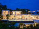 Luxurious modern villa with large glass windows and a swimming pool surrounded by lush greenery at dusk