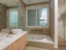 Modern bathroom with large mirrors, double sink, and bathtub