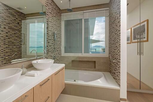 Modern bathroom with large mirrors, double sink, and bathtub