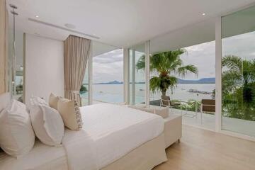 Luxurious bedroom with a large bed, floor-to-ceiling windows, and a stunning ocean view.