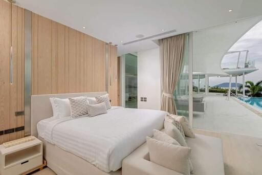 Modern bedroom with a large bed, wooden paneling, and a view of the pool