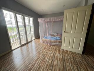 Bedroom with bed, mosquito net, large windows, and a door