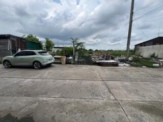 Outdoor area with a car, garbage, and green trees