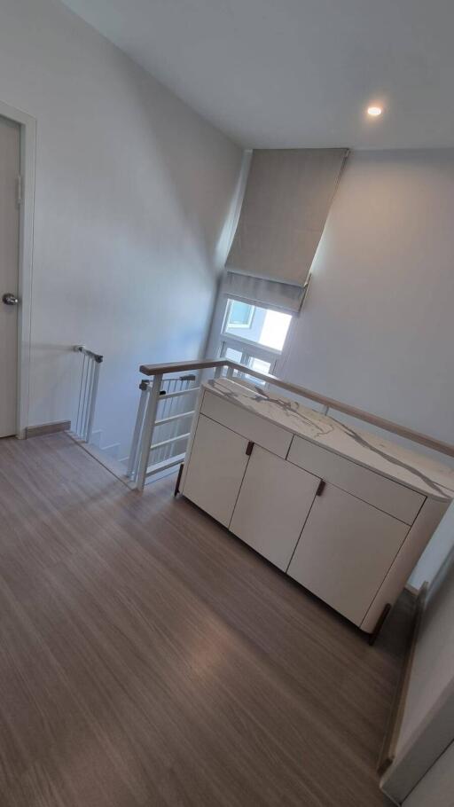 Upstairs hallway with cabinet, window, and baby gate