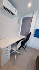 Modern home office with two chairs, desk, air conditioner, wall clock, and TV.