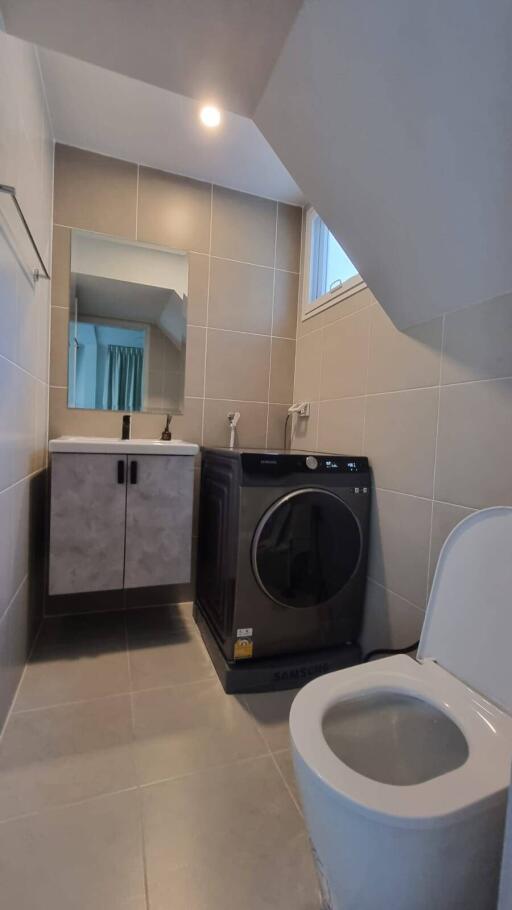 Modern bathroom with washer, vanity, mirror, and toilet