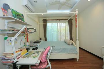 A cozy bedroom with a bed, study desk, and bookshelves