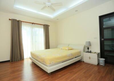 Spacious bedroom with wooden flooring, large bed, and ceiling fan