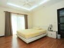 Spacious bedroom with wooden flooring, large bed, and ceiling fan