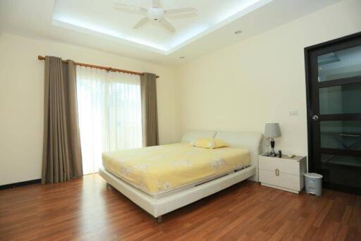 Spacious bedroom with wooden flooring, large bed, and ceiling fan