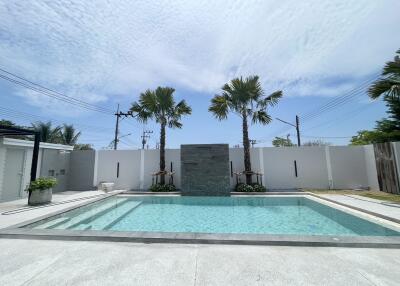 Modern outdoor swimming pool with palm trees and a stone water feature