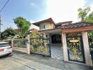 Front view of a residential house with a decorated gate and driveway