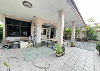 Photo of the exterior of a residential property with a covered porch area, plants, and tiled flooring