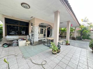 Photo of the exterior of a residential property with a covered porch area, plants, and tiled flooring