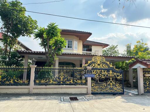 Front view of a two-story house with a decorative gate and lush greenery