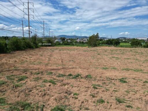 Open land area with clear sky and farmland in the background