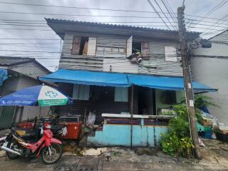 Exterior view of a two-story residential building with motorbike and street