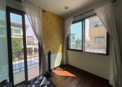 A cozy bedroom with large windows, sheer curtains, and wooden flooring