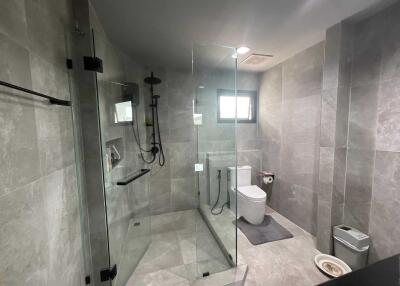 Modern bathroom with a glass-enclosed shower, toilet, and small window