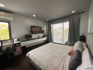 Modern bedroom with large bed, wall-mounted TV, and work area