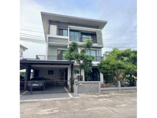 Modern three-story residential building with a carport and balcony