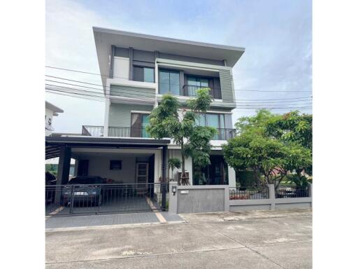 Modern three-story residential building with a carport and balcony