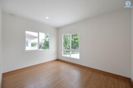 Bright and empty bedroom with wooden flooring and large windows.