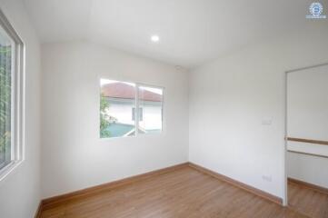 Empty bedroom with wooden flooring and two windows