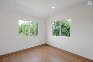 Empty bedroom with wooden floor and large windows