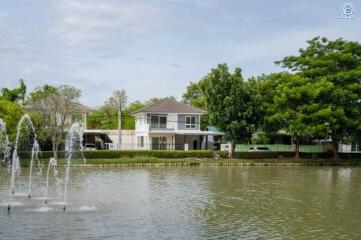 House by a pond with water fountain and green surroundings