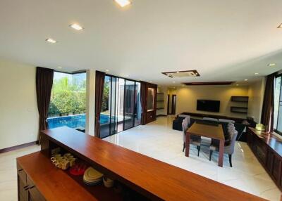 Spacious living room with large windows, a pool view, and modern furnishings
