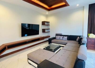 Modern living room with stylish ceiling design, comfortable sectional sofa, and mounted TV