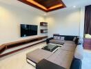 Modern living room with stylish ceiling design, comfortable sectional sofa, and mounted TV