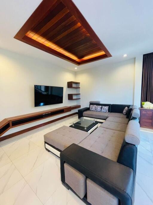 Modern living room with stylish ceiling design, comfortable sectional sofa, and mounted TV